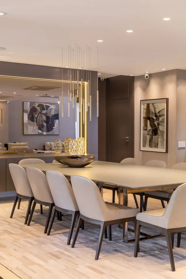 Sala de jantar com mesa para oito lugares e lustre pendente dourado