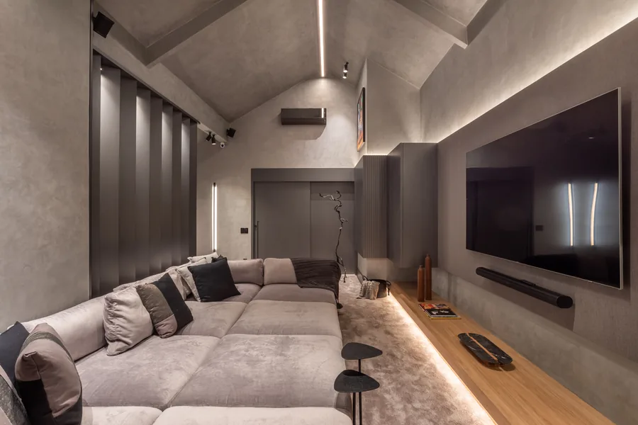 Sala de cinema com painéis ripados escuros e TV embutida