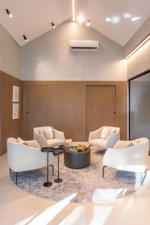 Sala de estar no sótão com painel em madeira e poltronas ao redor da mesa
