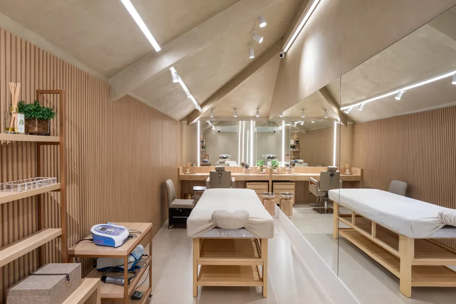 Sala de estética com painéis ripados em madeira, macas e bancadas com espelho