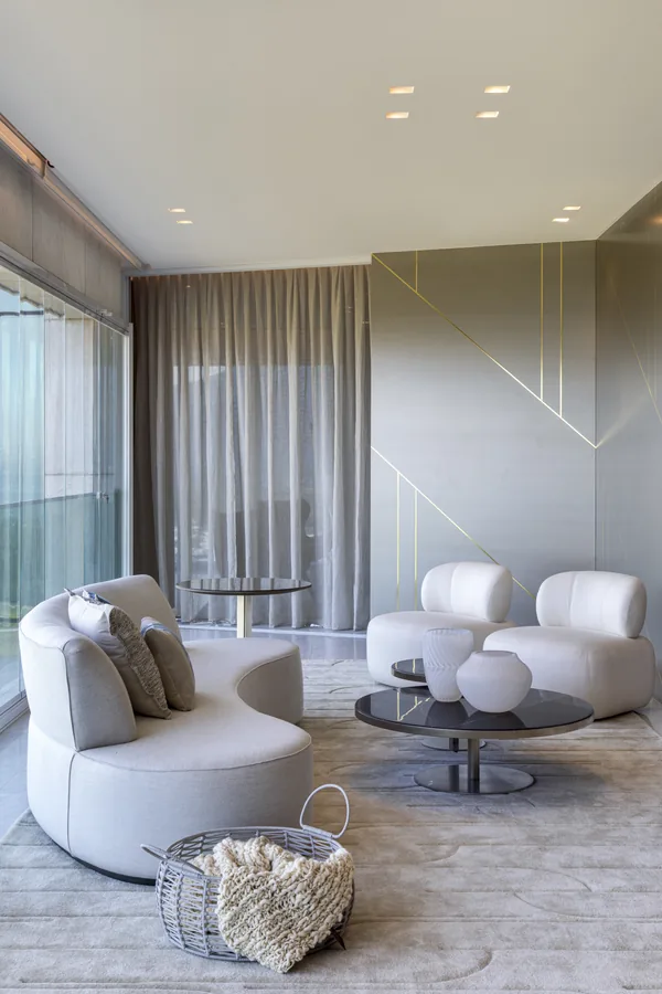 Sala de estar com painel em laca com frisos dourados e poltronas curvas