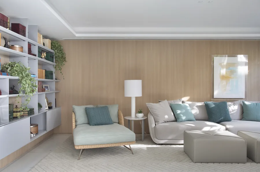 Sala de estar com painel em madeira clara e estante branca com nichos