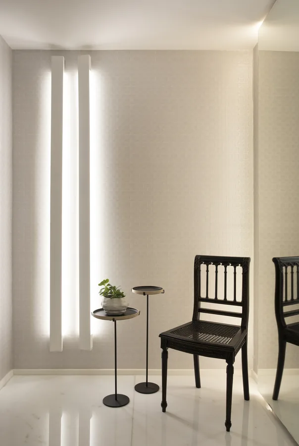 Hall com perfis de luz verticais e cadeira escura